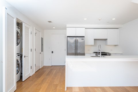 a white kitchen with a washer and dryer and white cabinets